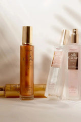 Absolute New York Silk Glow shimmer body collection on a tabletop with multiple bottles, featuring a Scented SHIMMER Body Mist in a warm, sunlit lifestyle scene.
